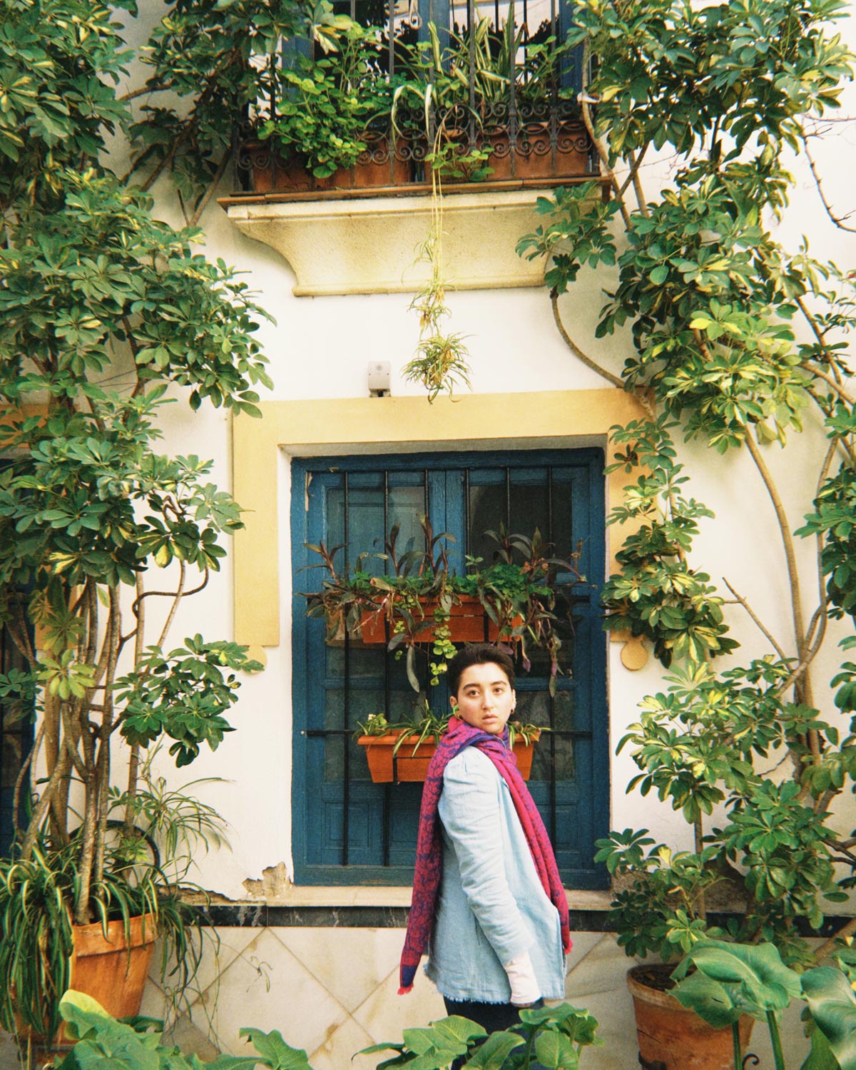 Morgan wearing a scarf and standing in front of a building covered in greenery in Spain