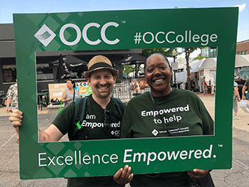 Two OCC staff posing with a frame at Arts, Beats & Eats.