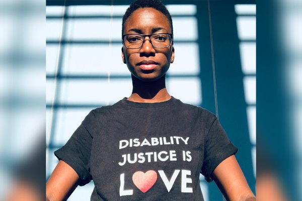 A person wearing a shirt that reads Disability Justice is Love