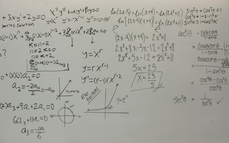 Mathematical equations written on a dry erase board.