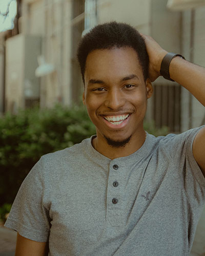 Kalen Rogers posing for a photo with his hand behind his head and the exterior of a building in the background.